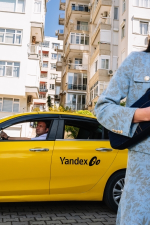 İstanbul'da Yandex Go taksisinin yanında akıllı telefonundan yolculuğunu planlayan bir kullanıcı.
