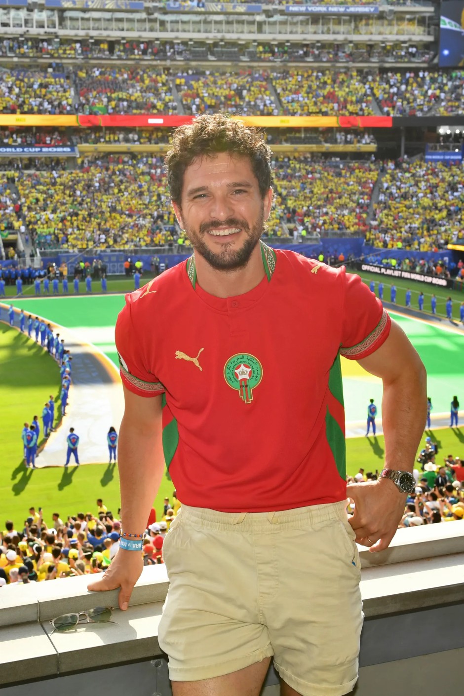 Kit Harington, Fas Milli Takımı formasını kısa krem şortla kombinleyerek Dünya Kupası maçını tribünden izliyor.
