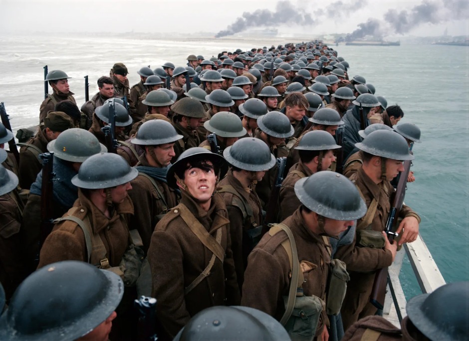 Christopher Nolan'ın Dunkirk (2017) filminden bir sahne; Dunkirk Tahliyesi sırasında askerlerle dolu bir gemi denizde ilerlerken uzakta dumanlar yükseliyor.