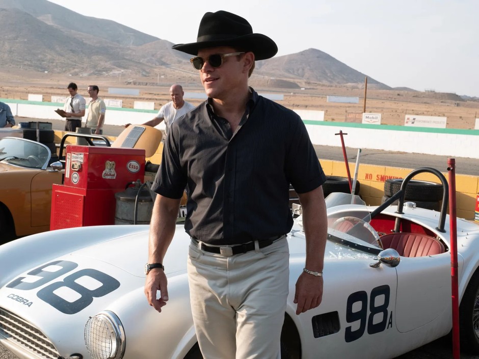 James Mangold'un Ford v Ferrari (2019) filminden bir sahne; Matt Damon'ın canlandırdığı Carroll Shelby, yarış pistinde klasik yarış otomobillerinin yanında yürüyor.