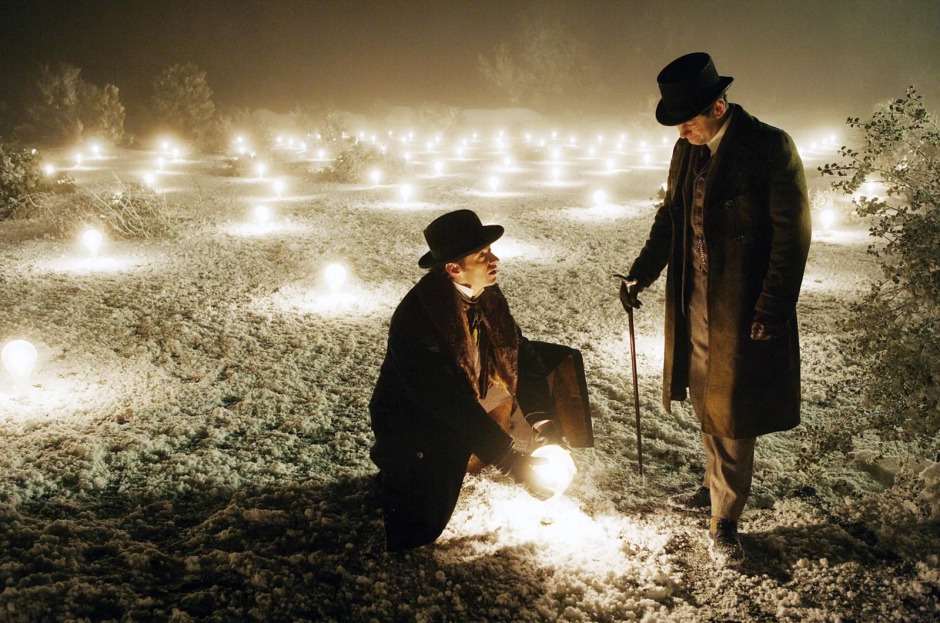 Christopher Nolan'ın The Prestige (2006) filminden bir sahne; iki sihirbaz, ampullerle aydınlatılmış bir alanda gece vakti karşı karşıya duruyor.