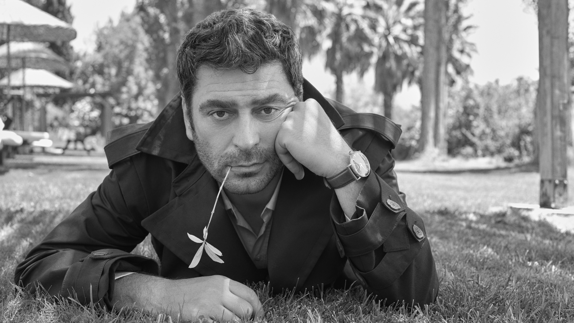 Ozan Akbaba, GQ Kapak çekimi için siyah-beyaz fotoğrafta çimenlerin üzerinde uzanmış, başını eline yaslayarak kameraya bakıyor.